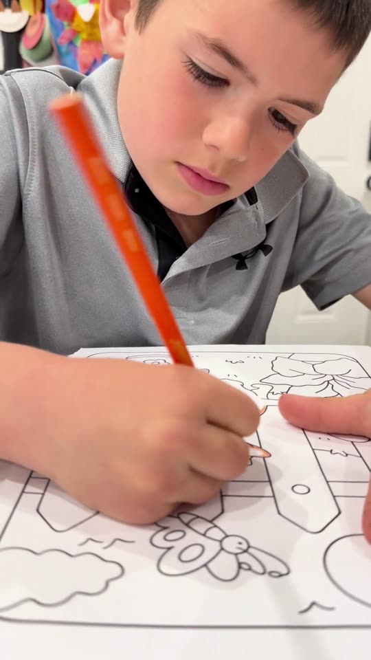 A boy coloring a page from the book